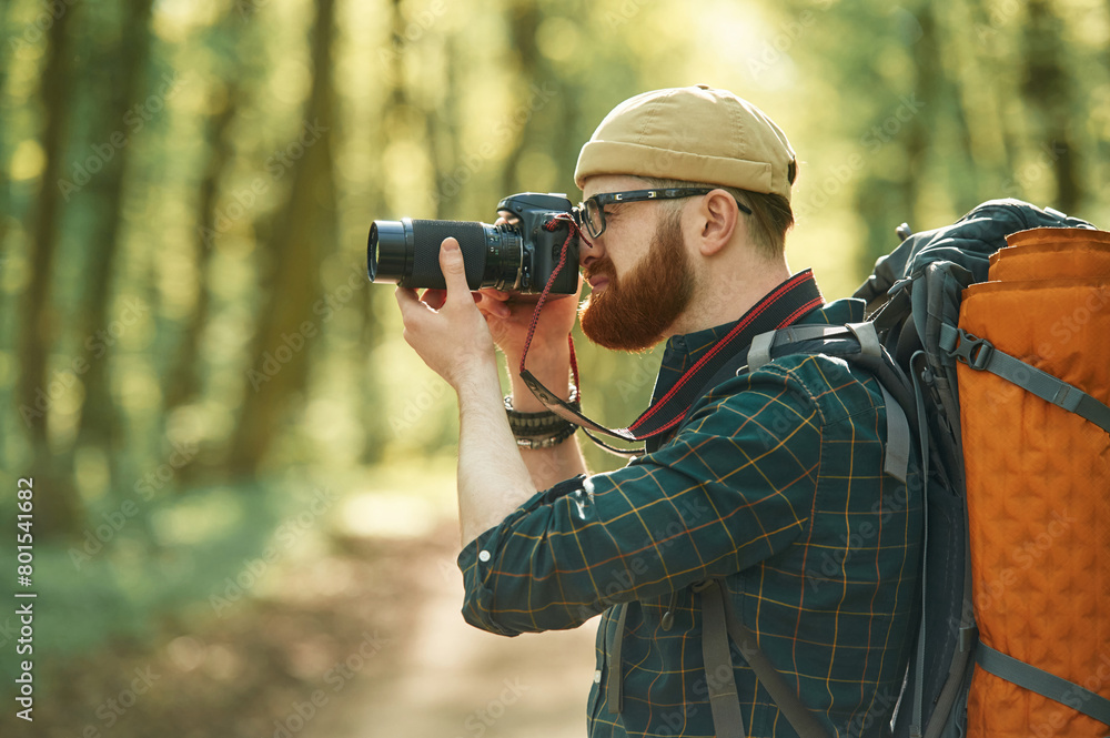 Fototapeta premium Professional photographer. Bearded man is in the forest at daytime