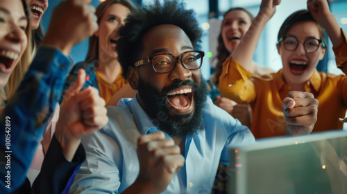 An emotional portrait of a group of office workers who are happy about completing a deal. People look at the computer screen, rejoice and have a great time photo
