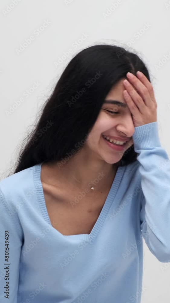 Positive portrait of a cheerful Indian woman playfully laughing and looking at camera, standing on white background. Vertical video. Positive portrait of a cheerful Indian woman playfully laughing and looking at camera, standing on white background. Vertical video.