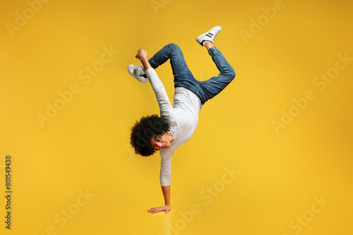 Canvas Print Black awesome man balancing on one hand on orange background