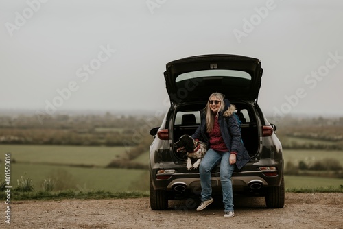 Woman and dog sitting at the back of her car