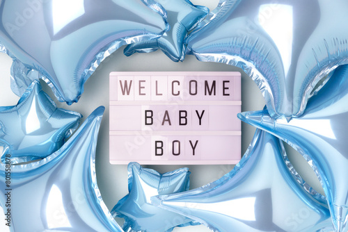 Welcome baby boy. Lightbox with letters and inflatable foil balloons in a blue color. Creative concept.