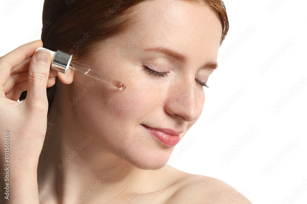 Beautiful woman with freckles applying cosmetic serum onto her face on white background