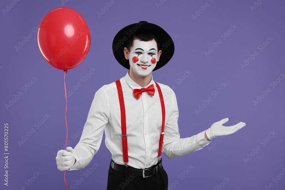 Funny mime artist with red balloon on purple background Funny mime artist with red balloon on purple background
