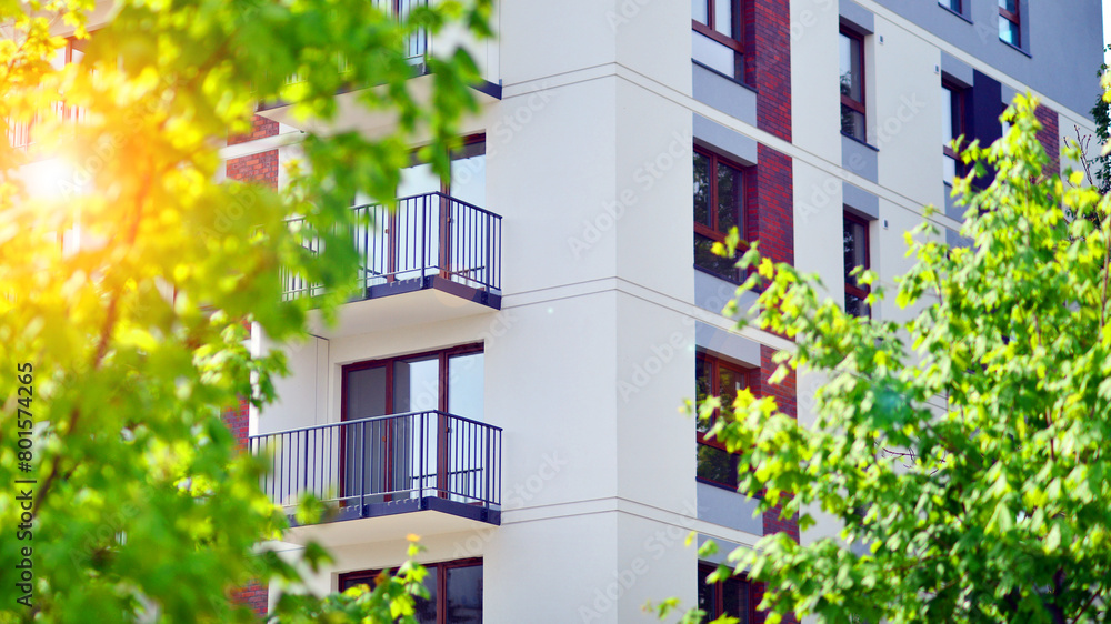 Modern residential building with new apartments in a green residential area. Eco architecture. Green tree and new apartment building. The harmony of nature and modernity. Modern residential building with new apartments in a green residential area. Eco architecture. Green tree and new apartment building. The harmony of nature and modernity.