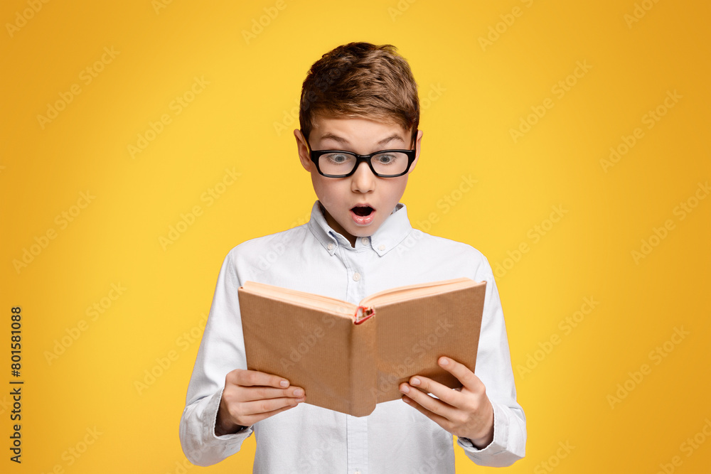 A young boy with glasses engrossed in reading a book. A young boy with glasses engrossed in reading a book.