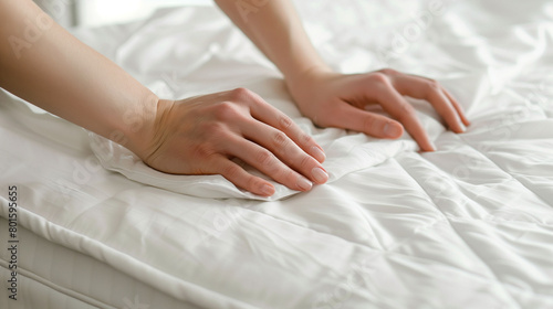 woman's hands making bed with white sheet on the bed in room, closeup