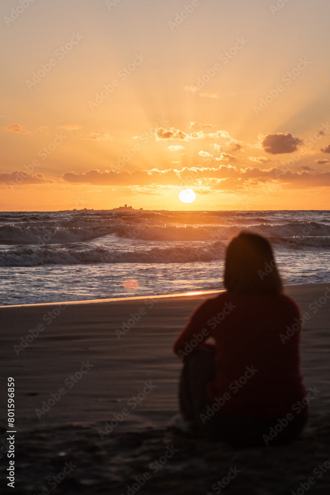 Woman on the beach contemplating the sunrise Woman on the beach contemplating the sunrise