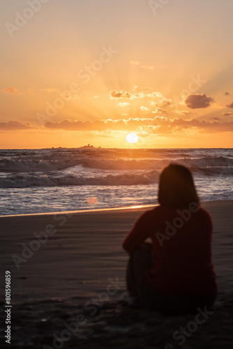 Woman on the beach contemplating the sunrise