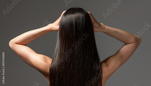 Asian woman with long straight hair her back to the camera and arms behind her head