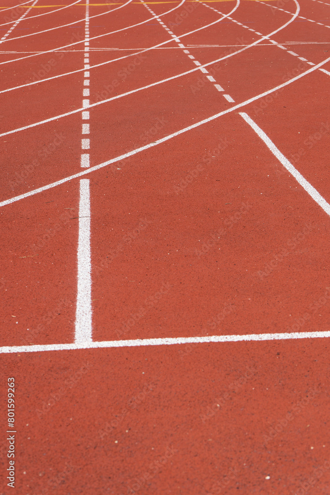 Close-up of a red athletic track with white lane marking and granular texture, at an outdoor sports center in Paris