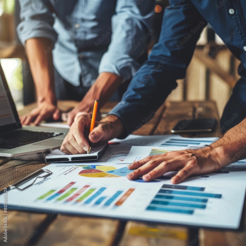 A photo of two people looking at a document with graphs and charts on it. A photo of two people looking at a document with graphs and charts on it.