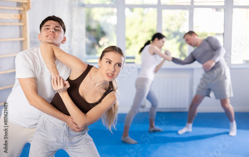 Sportive young woman practitioner of self-defense courses applying attack methods on young man