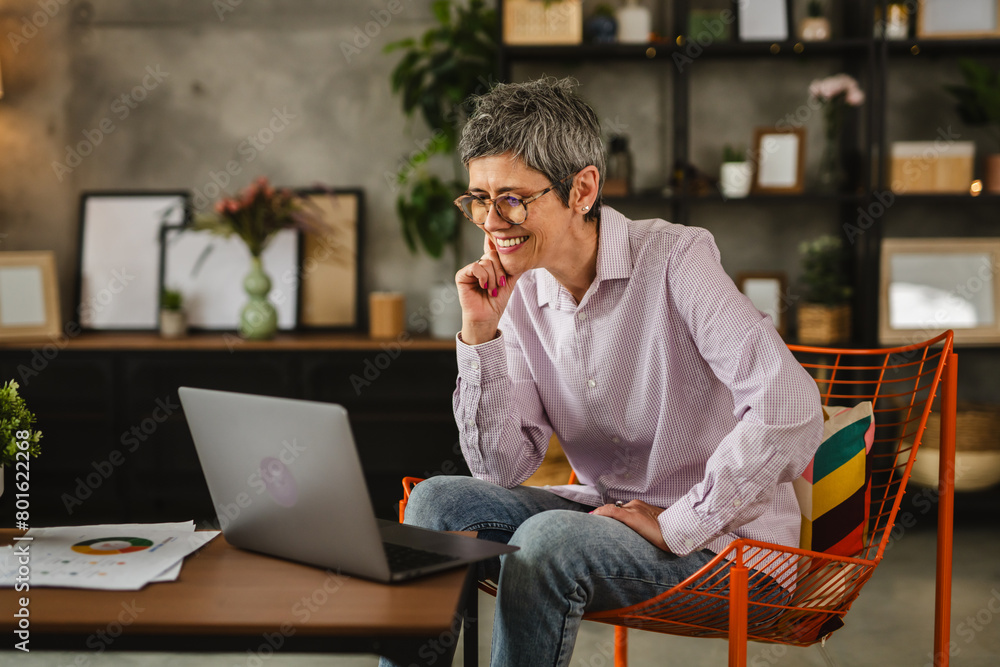 Mature woman with eyeglasses work from home on laptop smile positive Mature woman with eyeglasses work from home on laptop smile positive