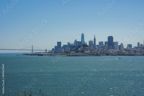 Panoramic view of San Francisco skyline from a vantage point, featuring San Francisco Bay, Bay Bridge, skyscrapers like Salesforce Tower and Transamerica Pyramid, serene atmosphere. photo