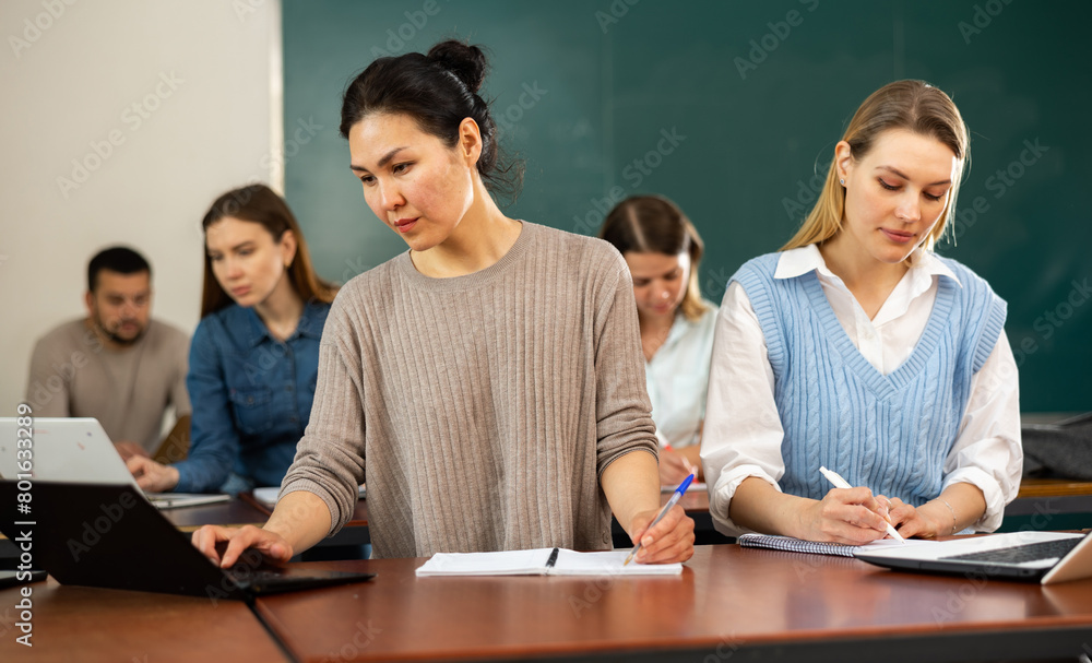 Fototapeta premium Asian and caucasian women university students sitting at table during lesson.