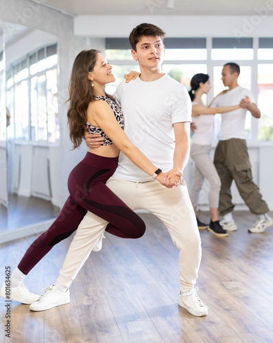 Young people learning tango dance at lessons in dance studio