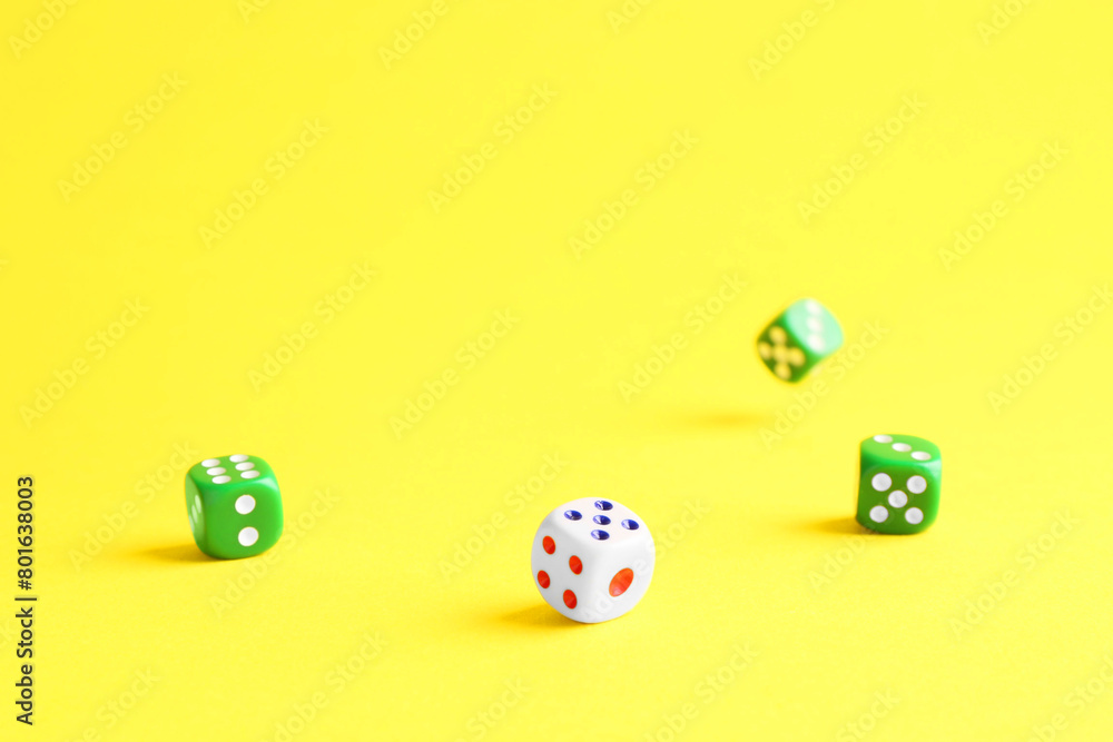 Many color game dices falling on yellow background Many color game dices falling on yellow background