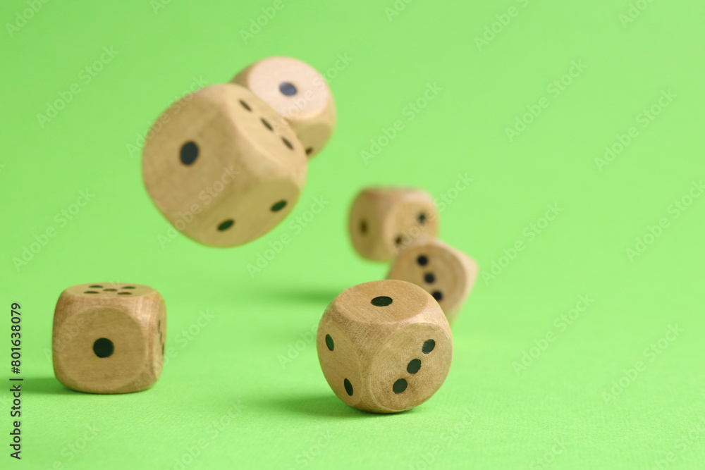 Many wooden game dices falling on green background, closeup. Space for text Many wooden game dices falling on green background, closeup. Space for text