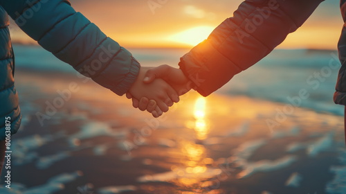 Two people hold hands against a backdrop of the ocean with the setting sun reflecting off the water, creating a warm, serene scene - Generative AI