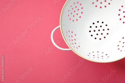 One clean empty colander on pink table, top view. Space for text