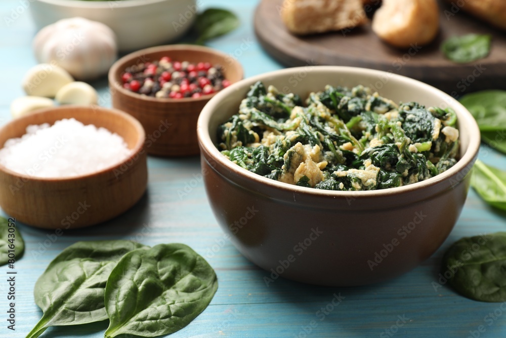 Tasty spinach dip with egg in bowl and spices on light blue wooden table, closeup Tasty spinach dip with egg in bowl and spices on light blue wooden table, closeup