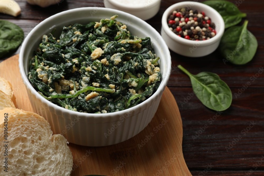 Tasty spinach dip with egg in bowl, bread and spices on wooden table, closeup Tasty spinach dip with egg in bowl, bread and spices on wooden table, closeup