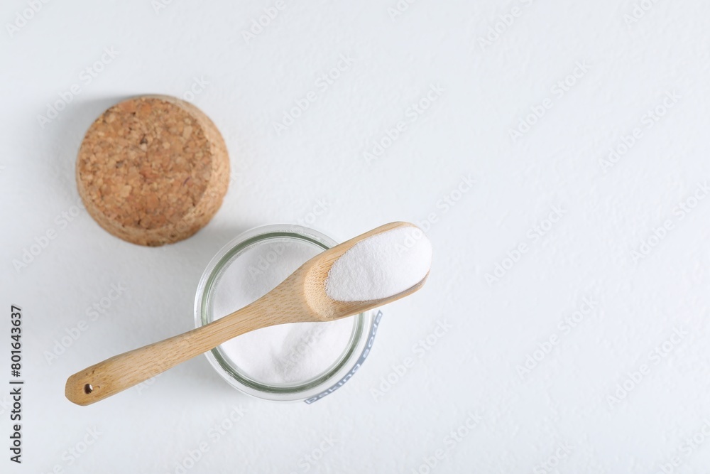 Baking soda in jar and spoon on white background, top view. Space for text Baking soda in jar and spoon on white background, top view. Space for text