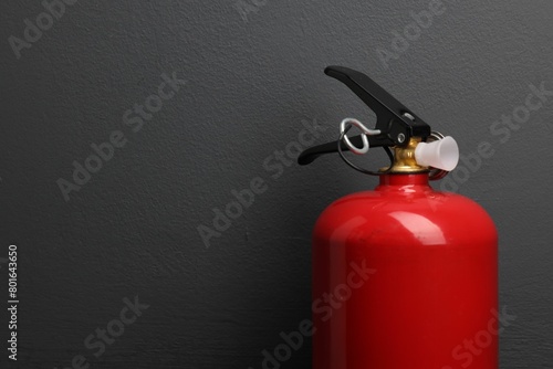 One fire extinguisher near grey wall, space for text