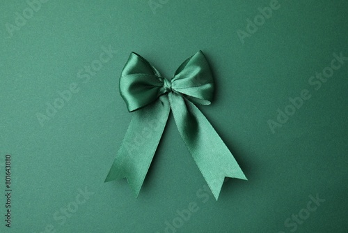Bright satin ribbon bow on green background, top view