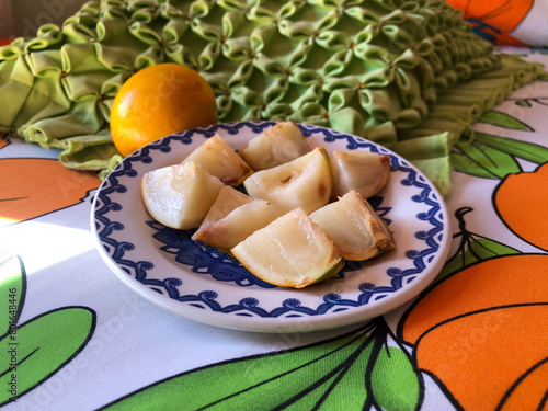 Abiu fruit cut into pieces on white porcelain plate with blue details photo