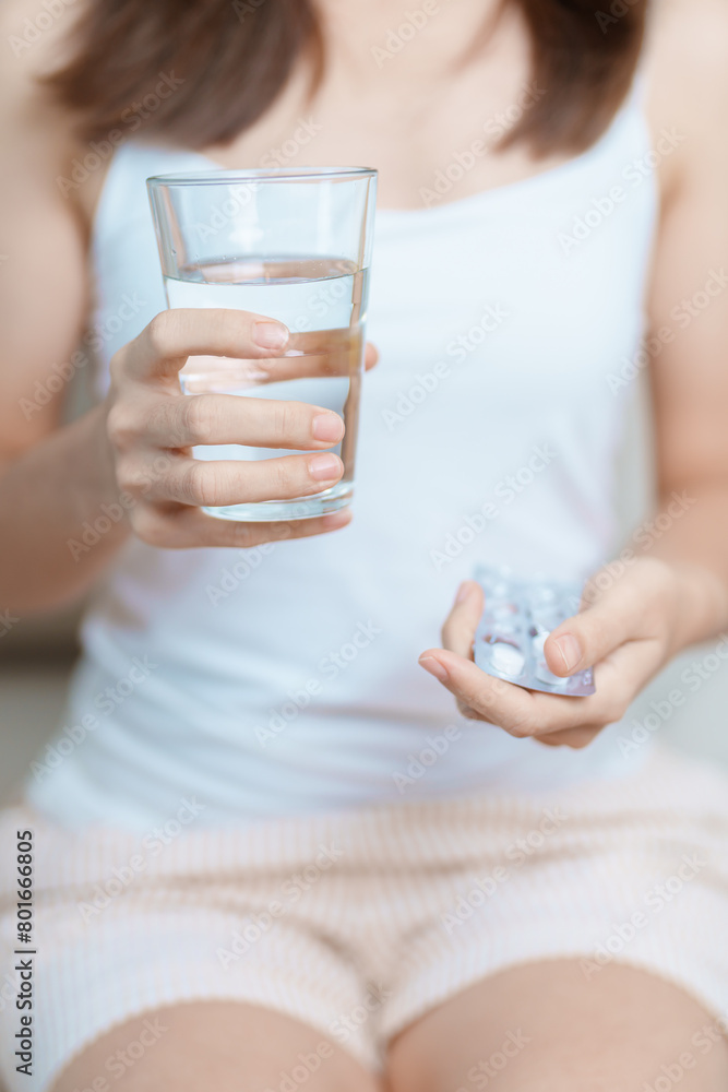woman hand holding medicine painkiller pill and water glass on the sofa at home, taking for headaches, stomach ache, Diarrhea Pain from food poisoning, Endometriosis, Hysterectomy and Menstrual woman hand holding medicine painkiller pill and water glass on the sofa at home, taking for headaches, stomach ache, Diarrhea Pain from food poisoning, Endometriosis, Hysterectomy and Menstrual