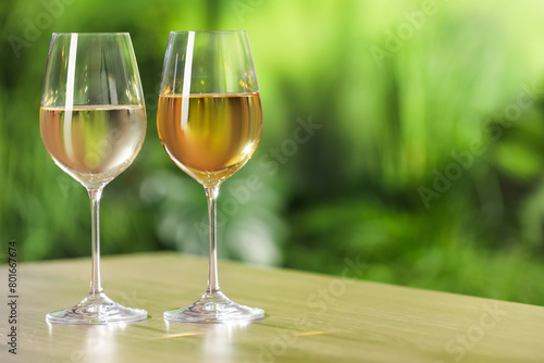 Tasty white wine in glasses on wooden table, space for text