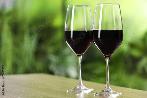 Tasty red wine in glasses on wooden table, space for text