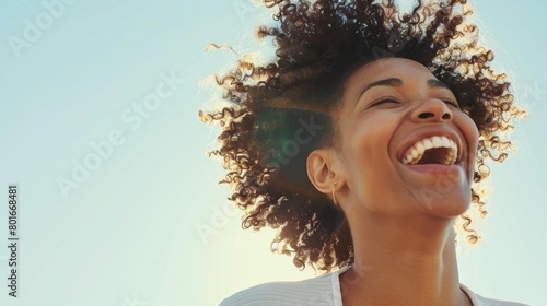 An overjoyed young woman with a hearty laugh, her curly hair beautifully backlit by the sun, evoking happiness. photo