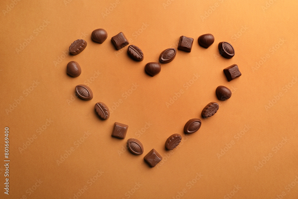Heart made with delicious chocolate candies on brown background, top view Heart made with delicious chocolate candies on brown background, top view