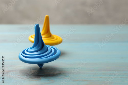 Foto Bright spinning tops on light blue wooden table, closeup
