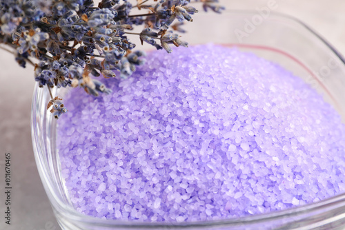 Violet sea salt in bowl and lavender flowers on table, closeup