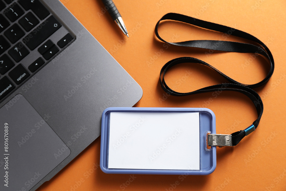 Blank badge, pen and laptop on orange background, top view Blank badge, pen and laptop on orange background, top view