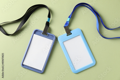 Blank badges with strings on light green background, top view
