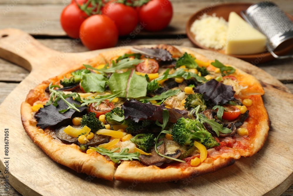 Delicious vegetarian pizza and ingredients on wooden table, closeup