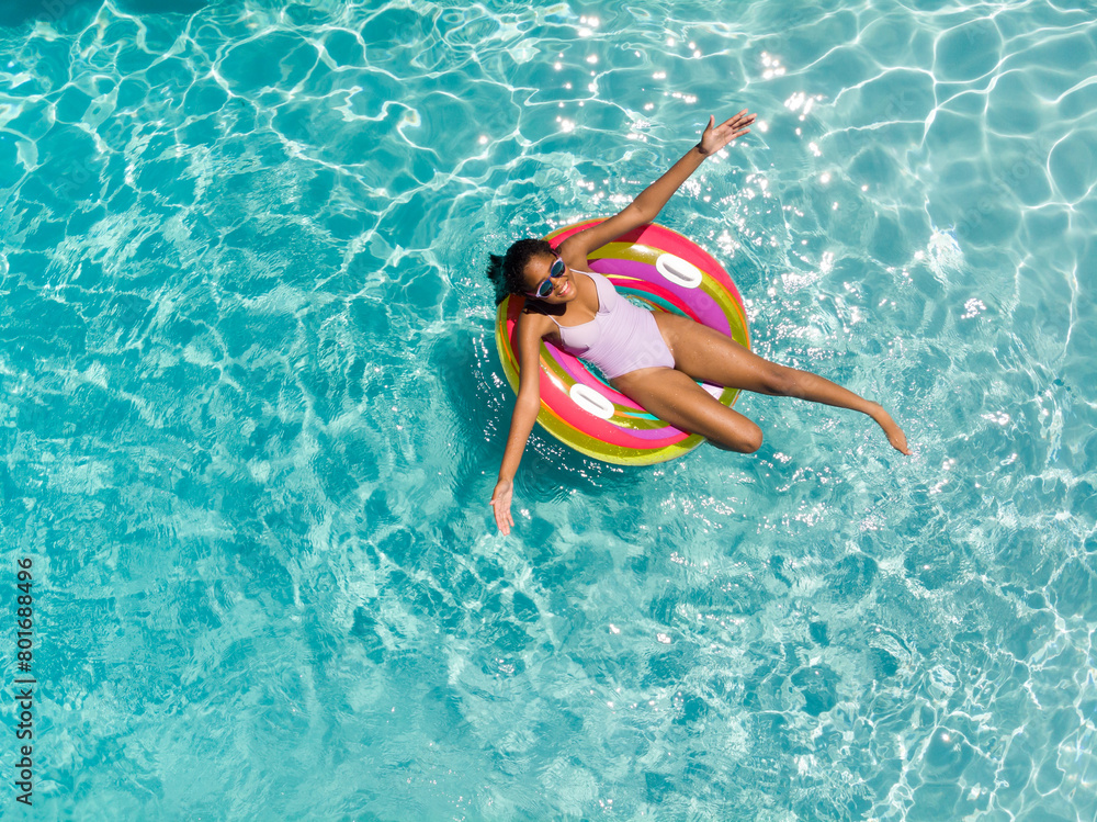 Teenage biracial girl enjoys a sunny day in the pool, with copy space