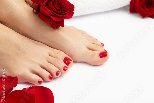 Woman with stylish red toenails after pedicure procedure and rose flowers on white background, closeup. Space for text