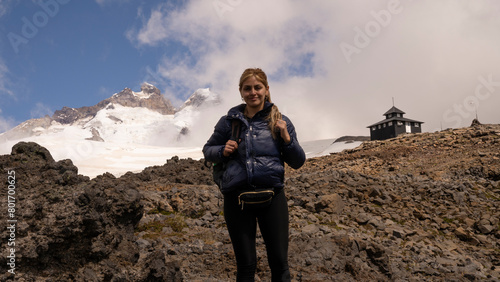 Outdoor activities. Extreme sports. Portrait of a woman hiking high in the Andes cordillera. The Tronador hill peak and Otto Meiling wooden refuge in the background photo