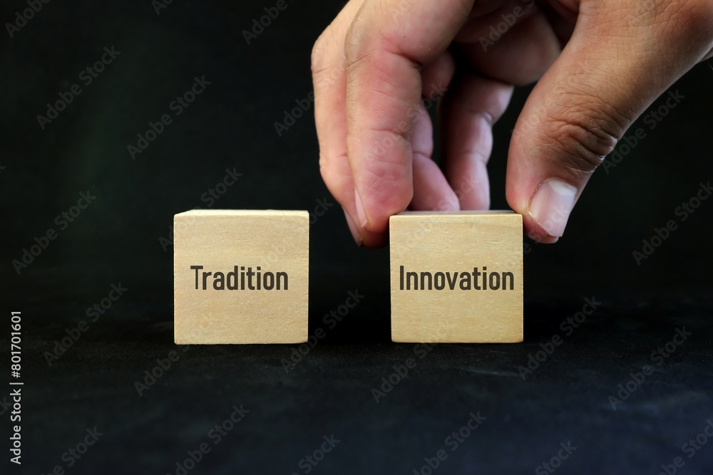 Hand choosing innovation over tradition concept. Wooden blocks on black background.
