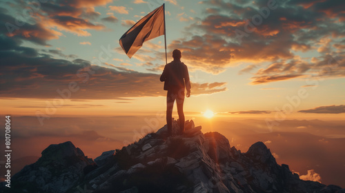 A man stands on a mountain top holding a flag