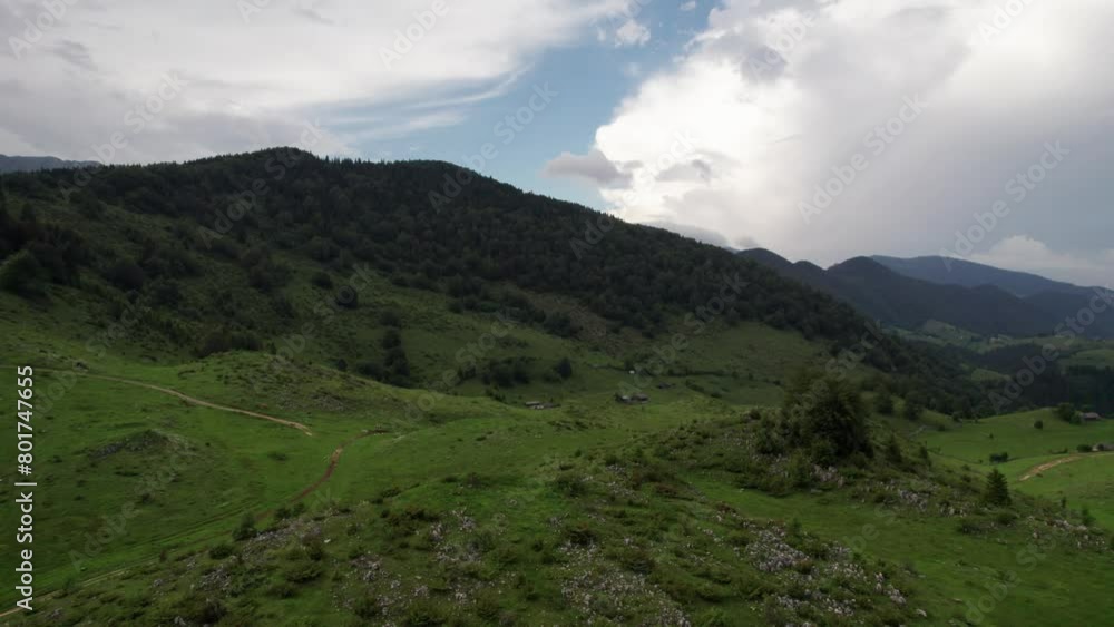 Lush hills near a village under a cloudy sky, tranquil and expansive landscape, aerial view Lush hills near a village under a cloudy sky, tranquil and expansive landscape, aerial view