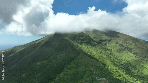 Aerial view. Clouds over the top of Mont Pelée volcano on the tropical island of Martinique. Beautiful mountain in green bushes above the Caribbean Sea.