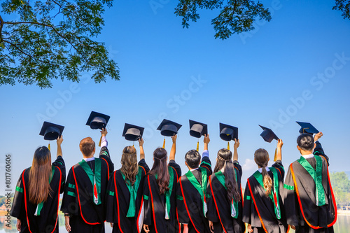 cheerful graduates in black gowns Graduation Caps Thrown in blue summer sky