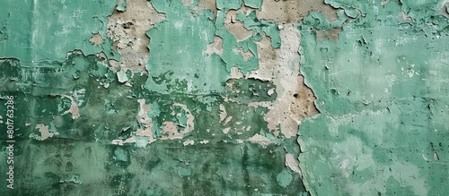 Close-up of a weathered green wall with cracks and peeling paint, showing signs of aging and neglect